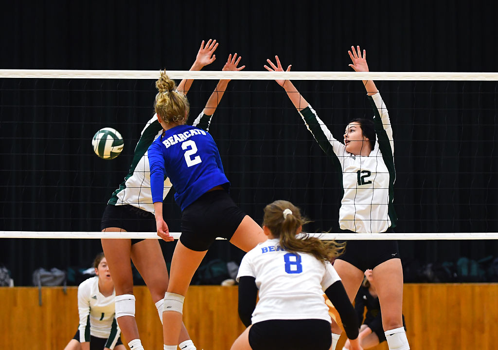 Hermann volleyball player, Grace Winkelmann spikes the ball past Rock Bridge blockers